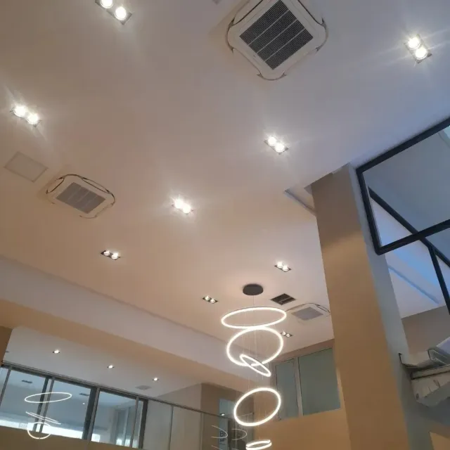 Techo con luces empotradas, rejillas de ventilación de climatización y una lámpara LED espiral colgante en un interior moderno.