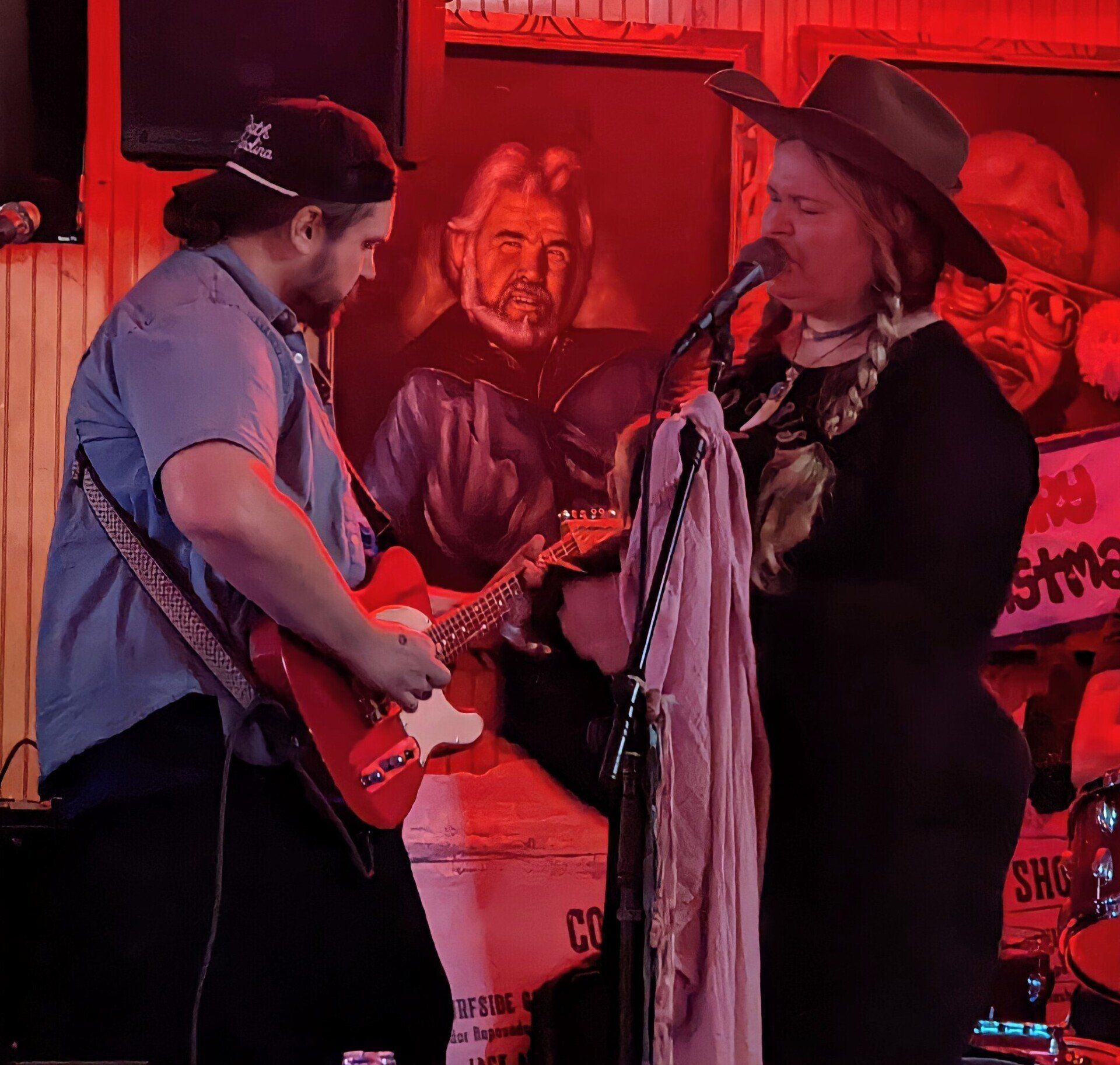 A man is playing a guitar and a woman is singing into a microphone.