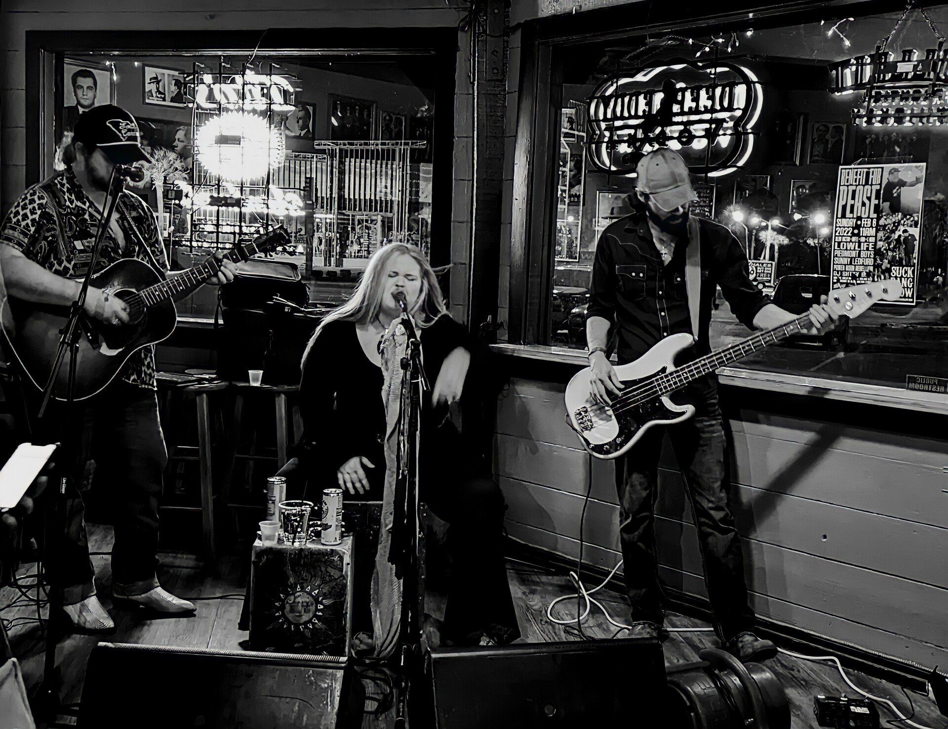 A black and white photo of a band playing instruments in a bar.