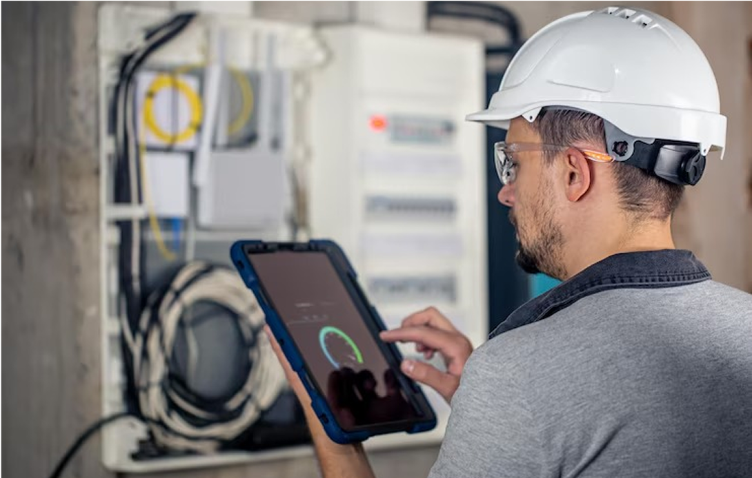 A man in a hard hat is using a tablet computer.