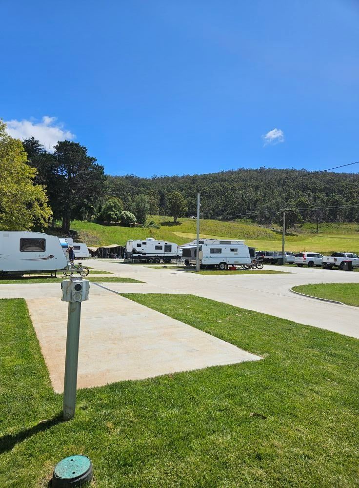 RVs Parked In A Grassy Campground Under A Clear Blue Sky — Dover Caravan Park in Dover, TAS
