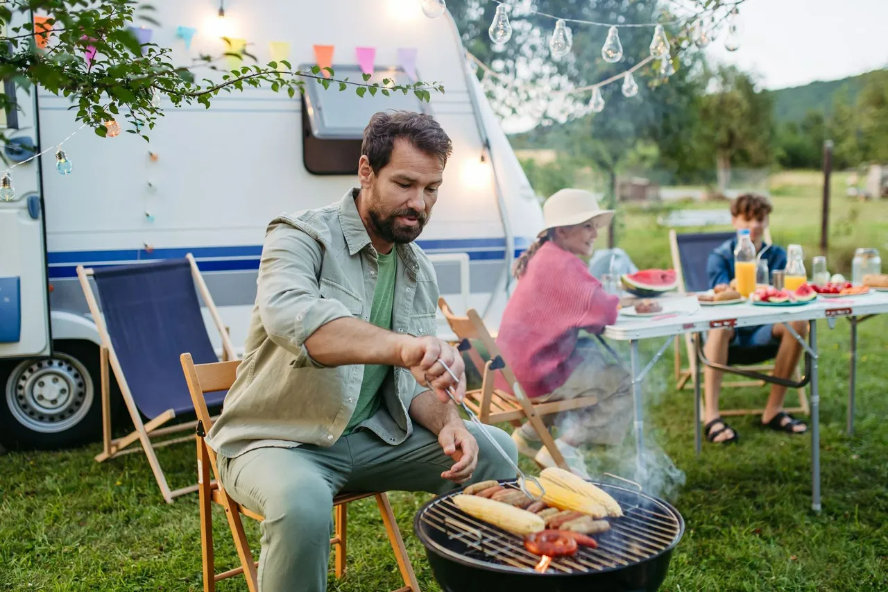 MAN Grilling Sausages At A Campsite, With A Camper Van — Dover Caravan Park in Dover, TAS