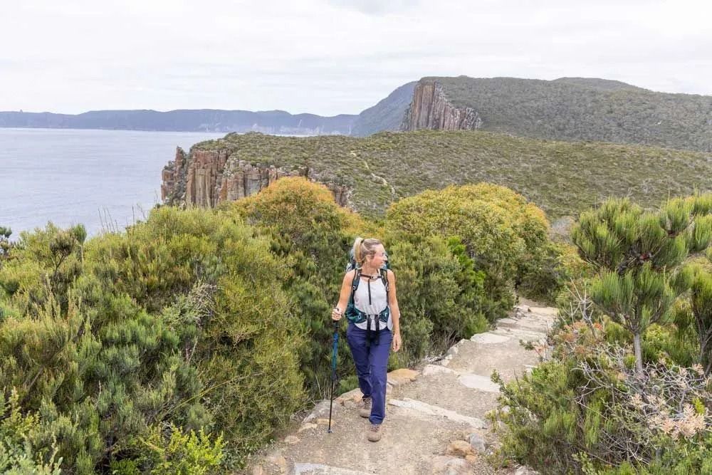 Hiker On A Stone Trail Overlooking Green Cliffs And Calm Water — Dover Caravan Park in Dover, TAS