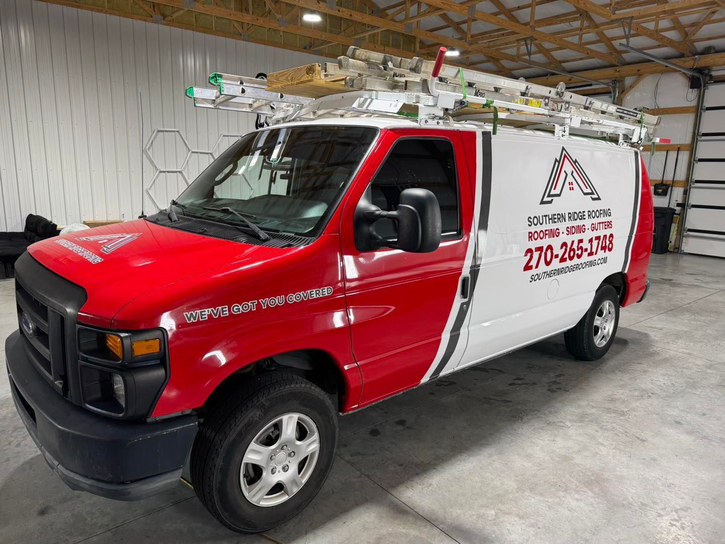 Red and white Scott Chambers HVAC van with ladders on the roof, parked in a garage.