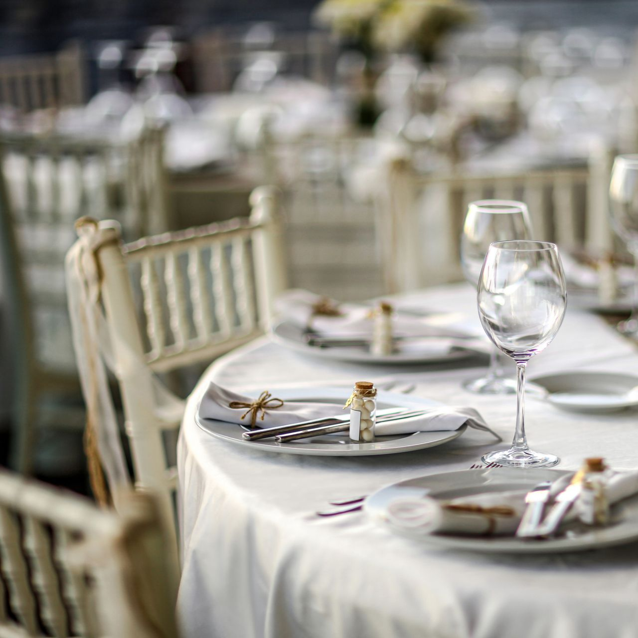Wedding reception table set with white linens, plates, silverware, and glassware.
