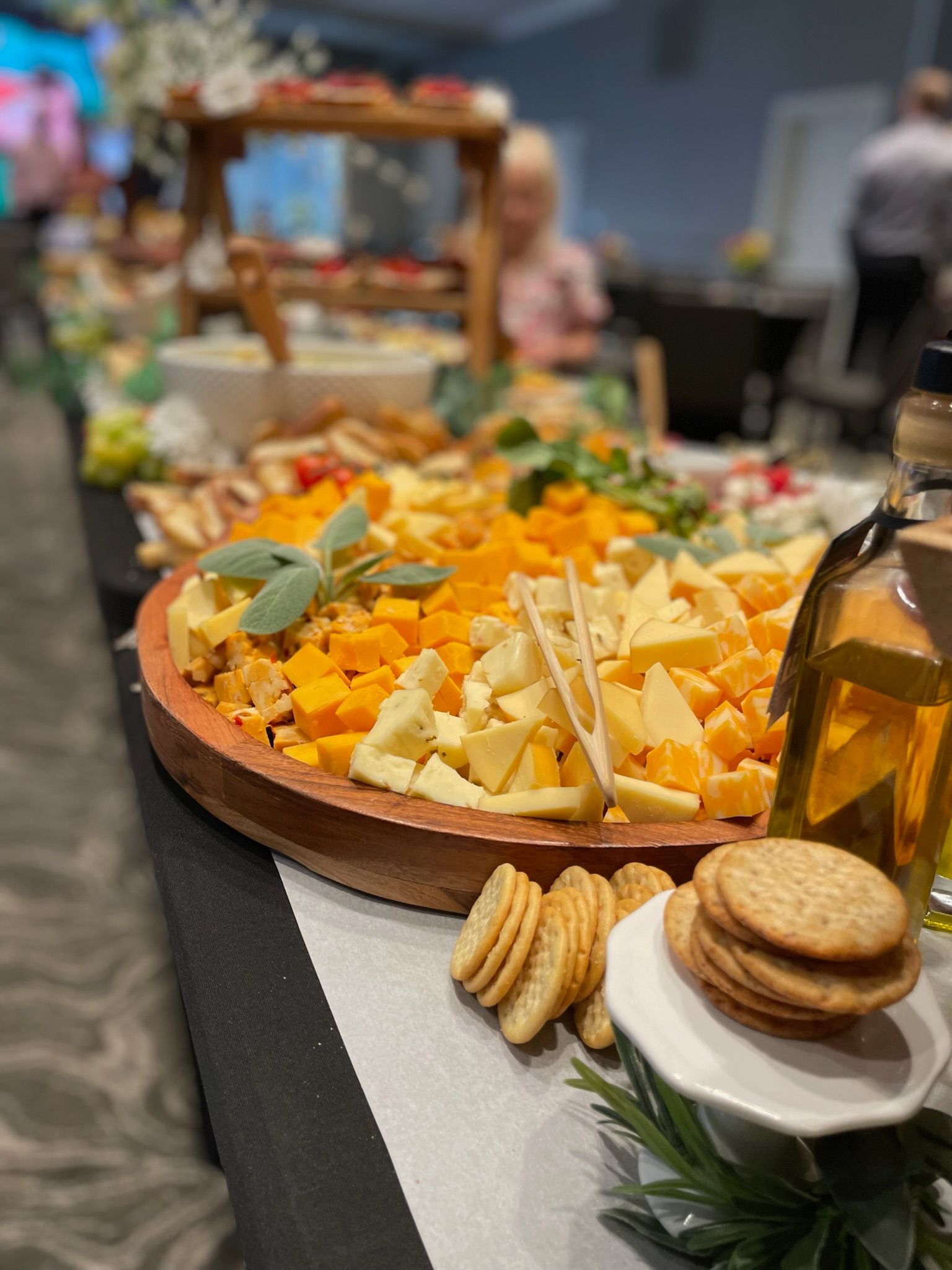 Buffet platter of assorted cheeses, crackers, and grapes on a table at an indoor event