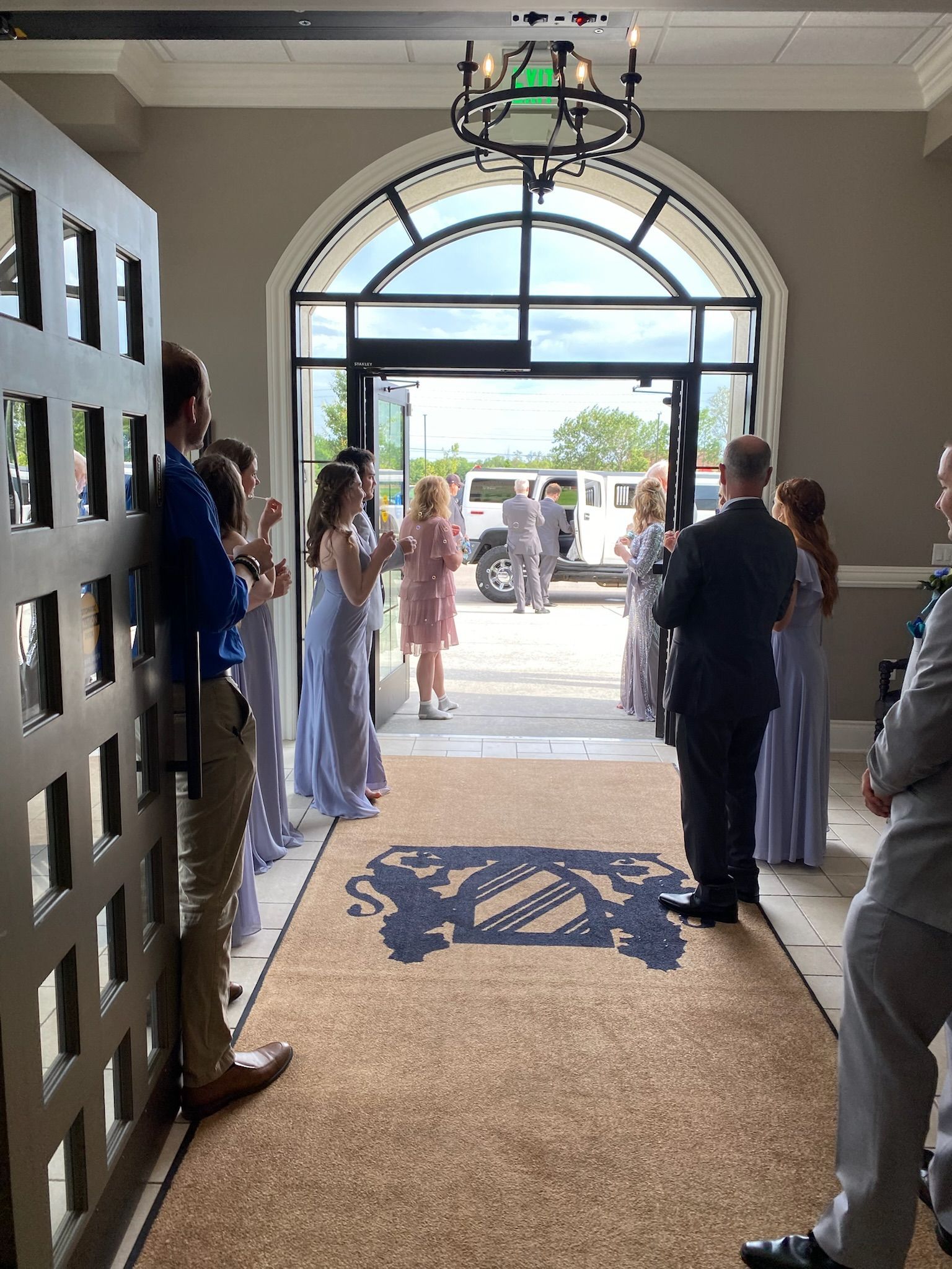 People standing in a bright arched hallway, looking out toward a sunny entrance.