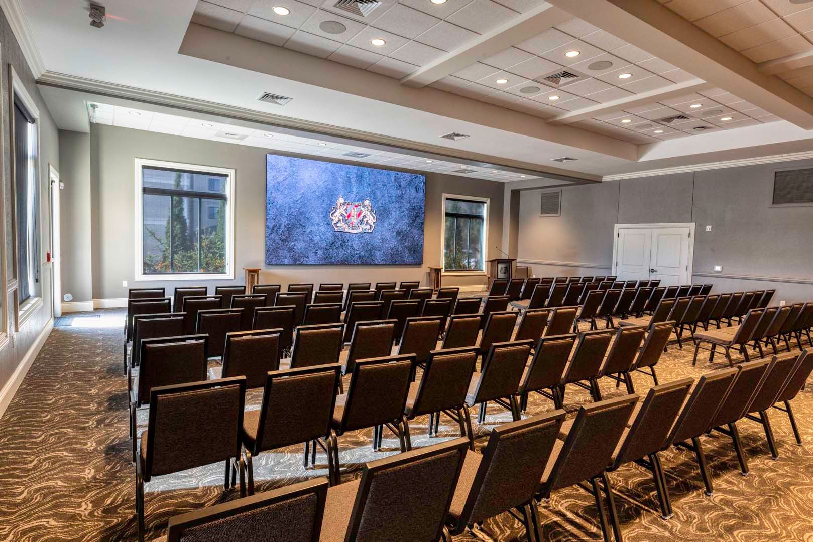Empty conference room with rows of chairs facing a large presentation screen and flip chart.