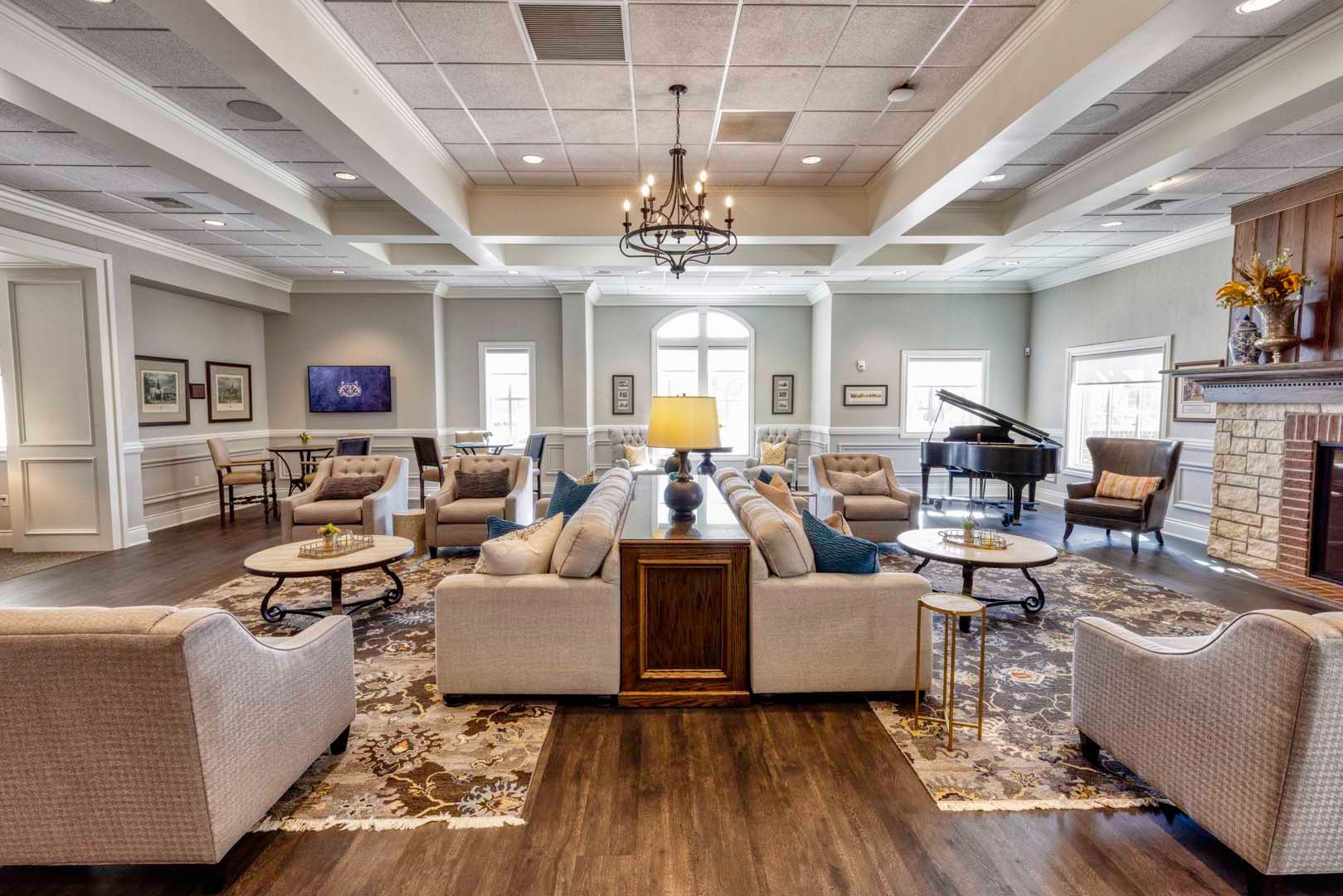 Elegant living room with beige sofas, fireplace, grand piano, and chandelier on wood floors