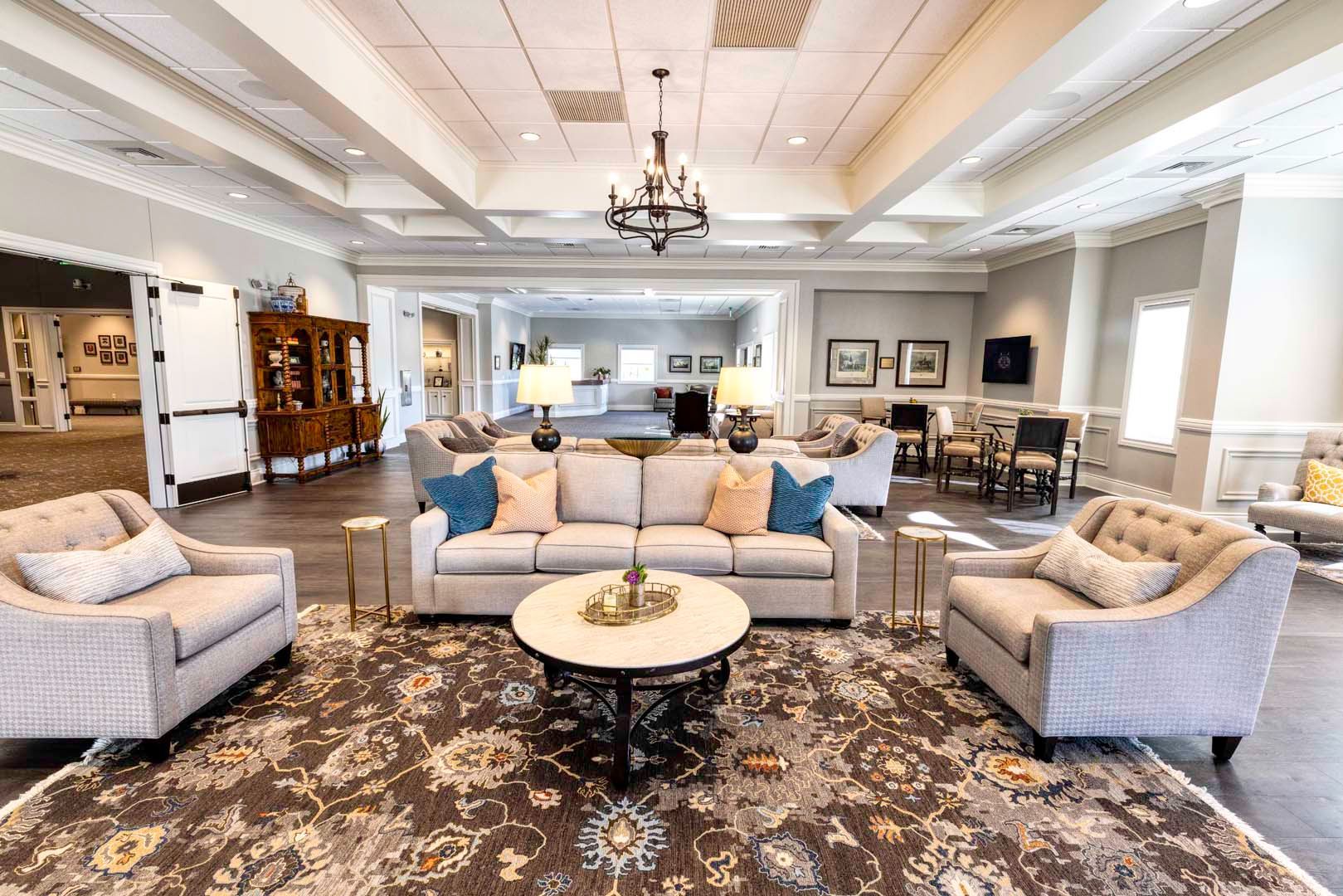Elegant living room with cream sofas, patterned rug, chandelier, and coffee tables in a bright open space