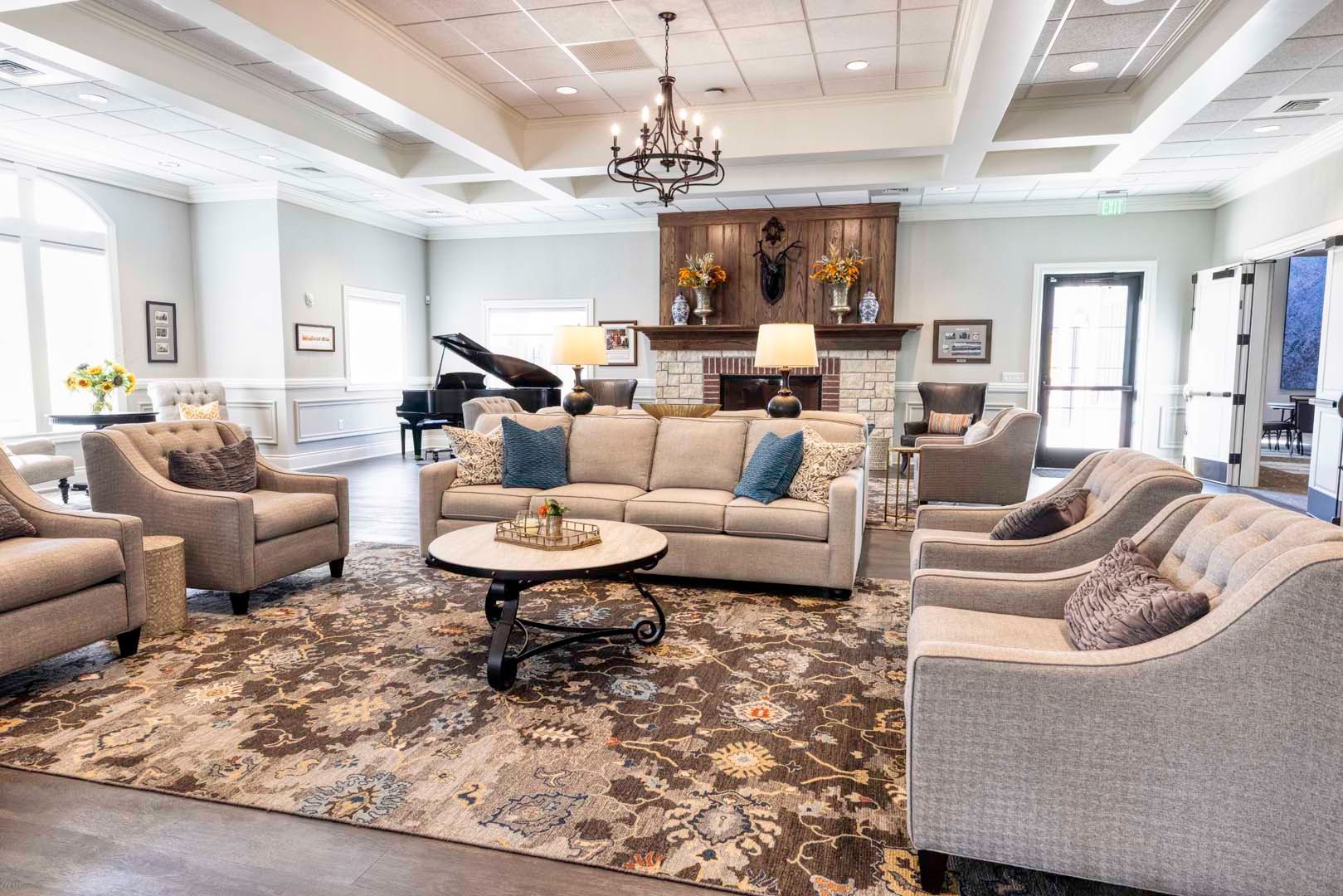 Elegant living room with beige sofas, patterned rug, piano, and chandelier under bright windows