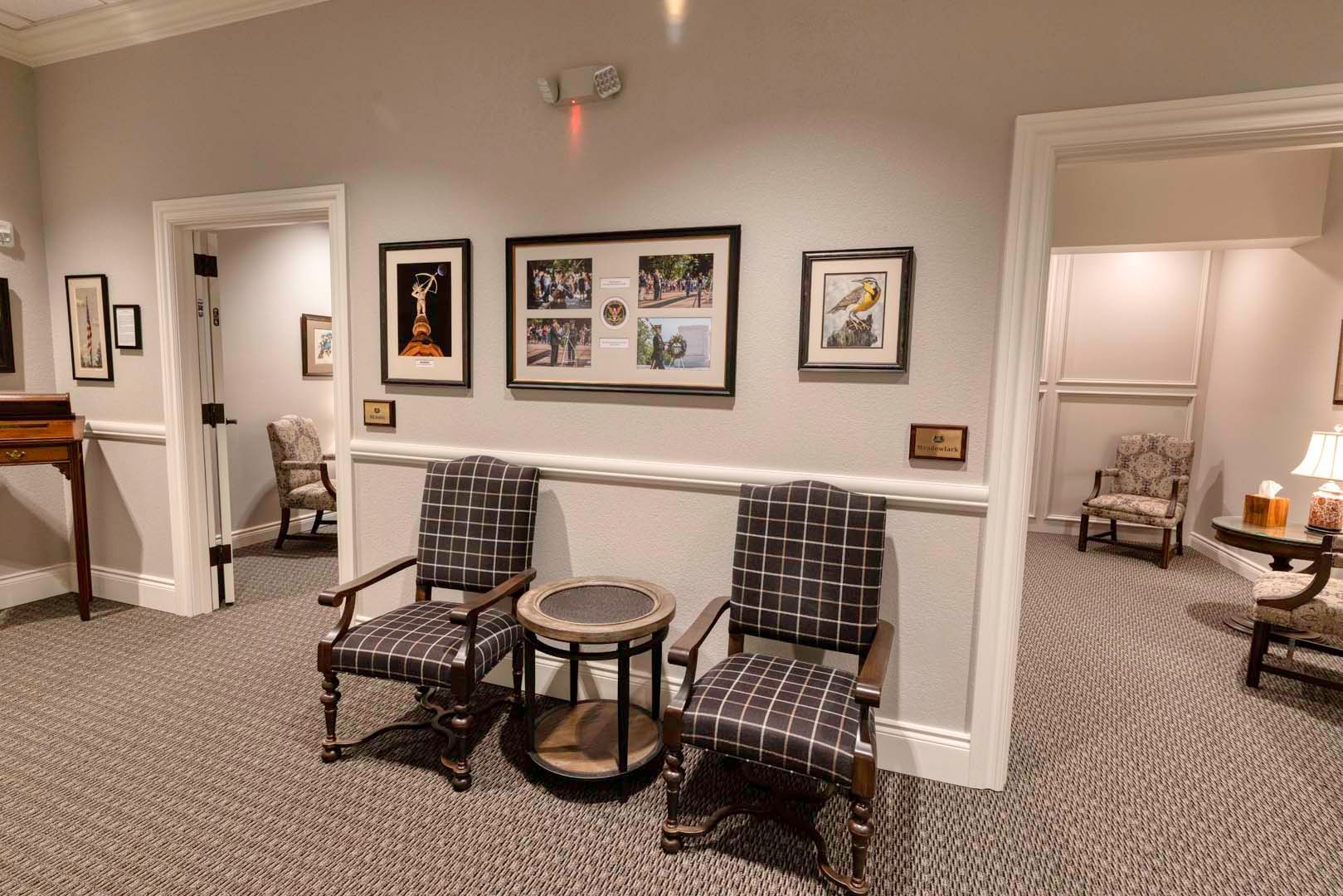 Hallway lounge with patterned chairs, round table, and framed artwork on cream walls