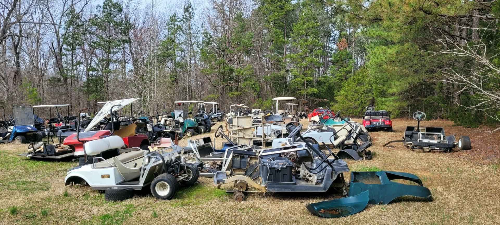 A bunch of golf carts are sitting in a field.
