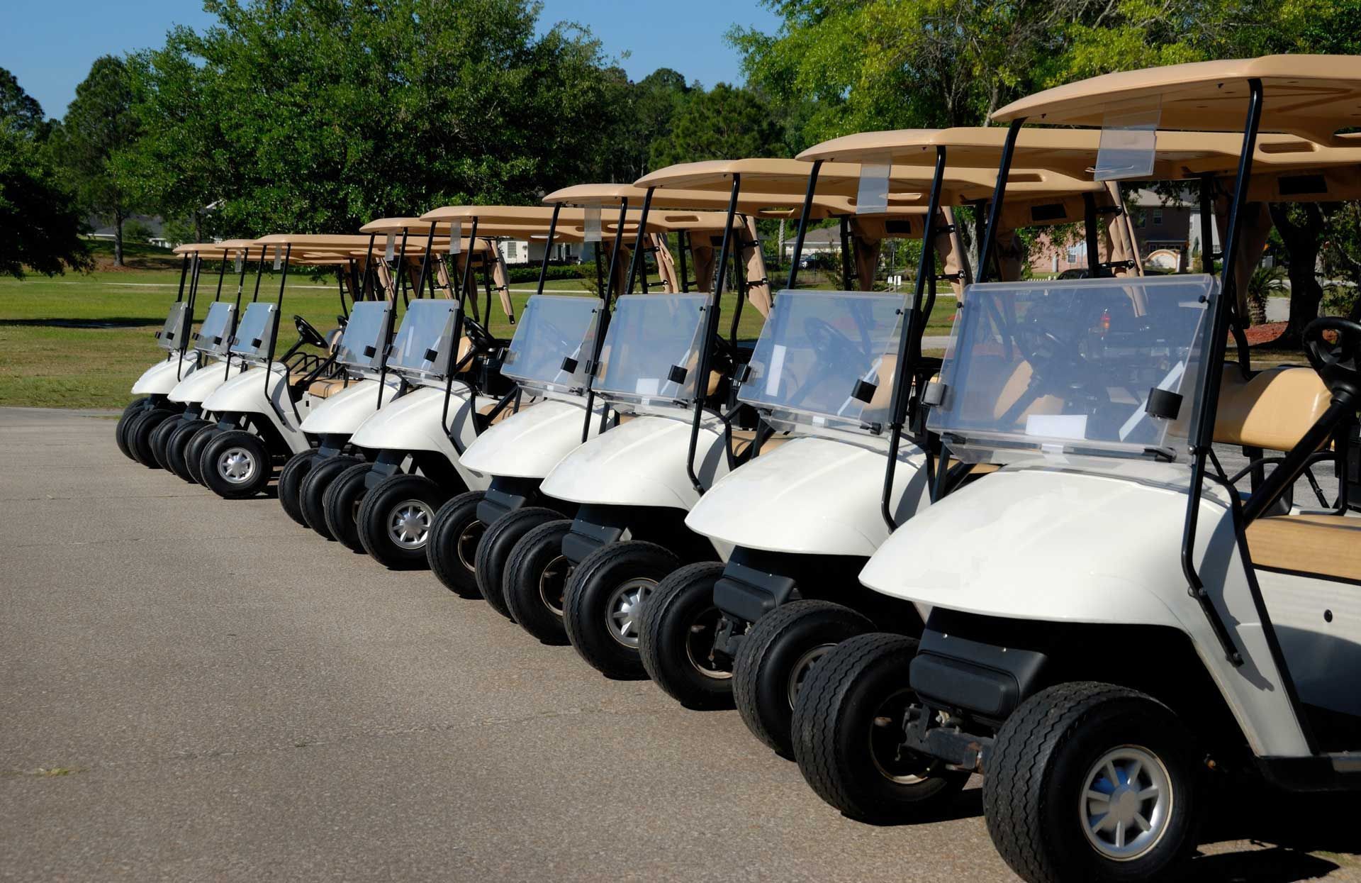 A row of golf carts are parked in a parking lot