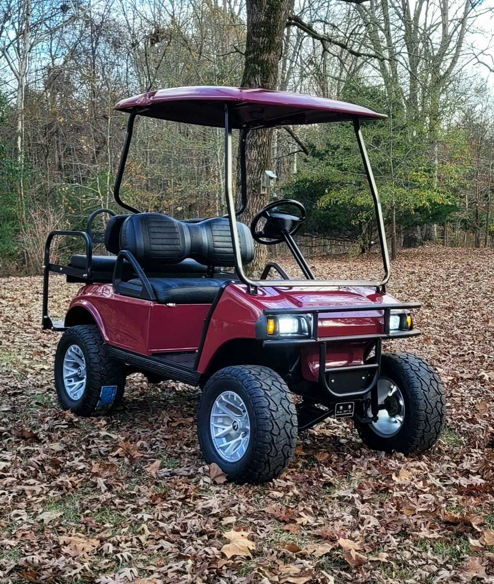 A red golf cart is parked in a pile of leaves.