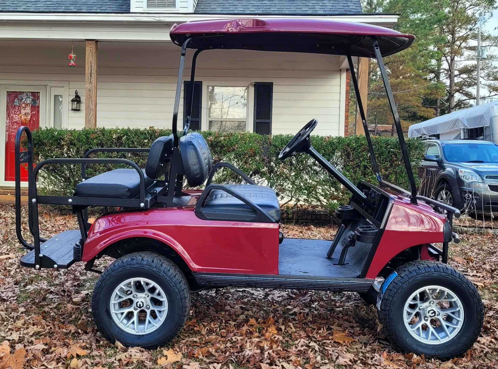 A red golf cart is parked in front of a house.