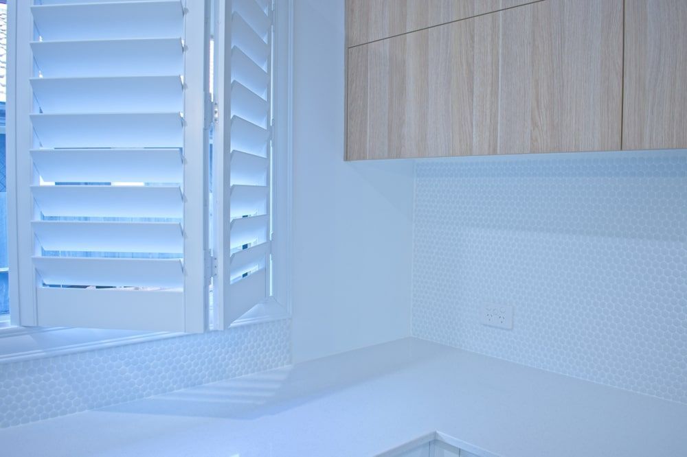 A Bathroom With White Shutters On The Window And Wooden Cabinets — Budget Home Improvements In Tweed Heads South, NSW