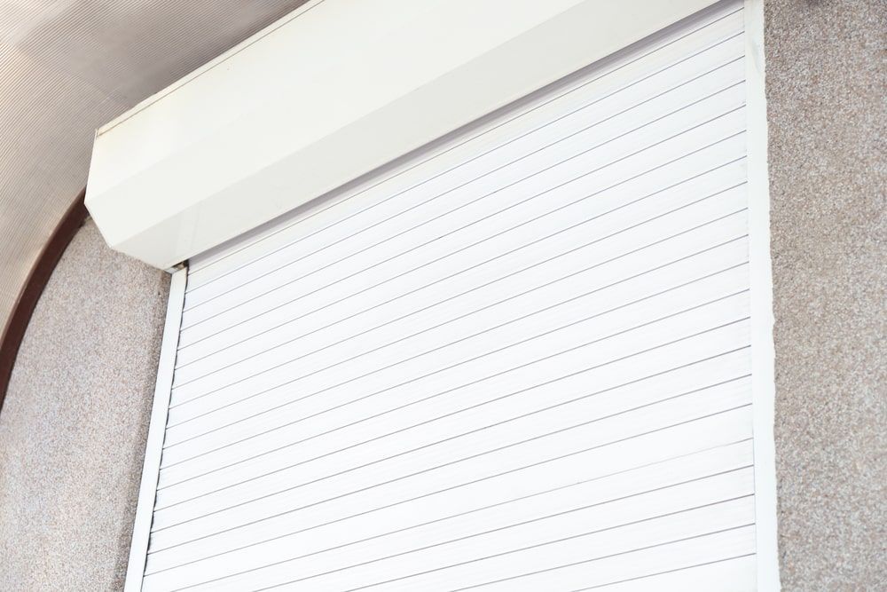 A Close Up Of A White Roller Shutter On A Window — Budget Home Improvements In Tweed Heads South, NSW
