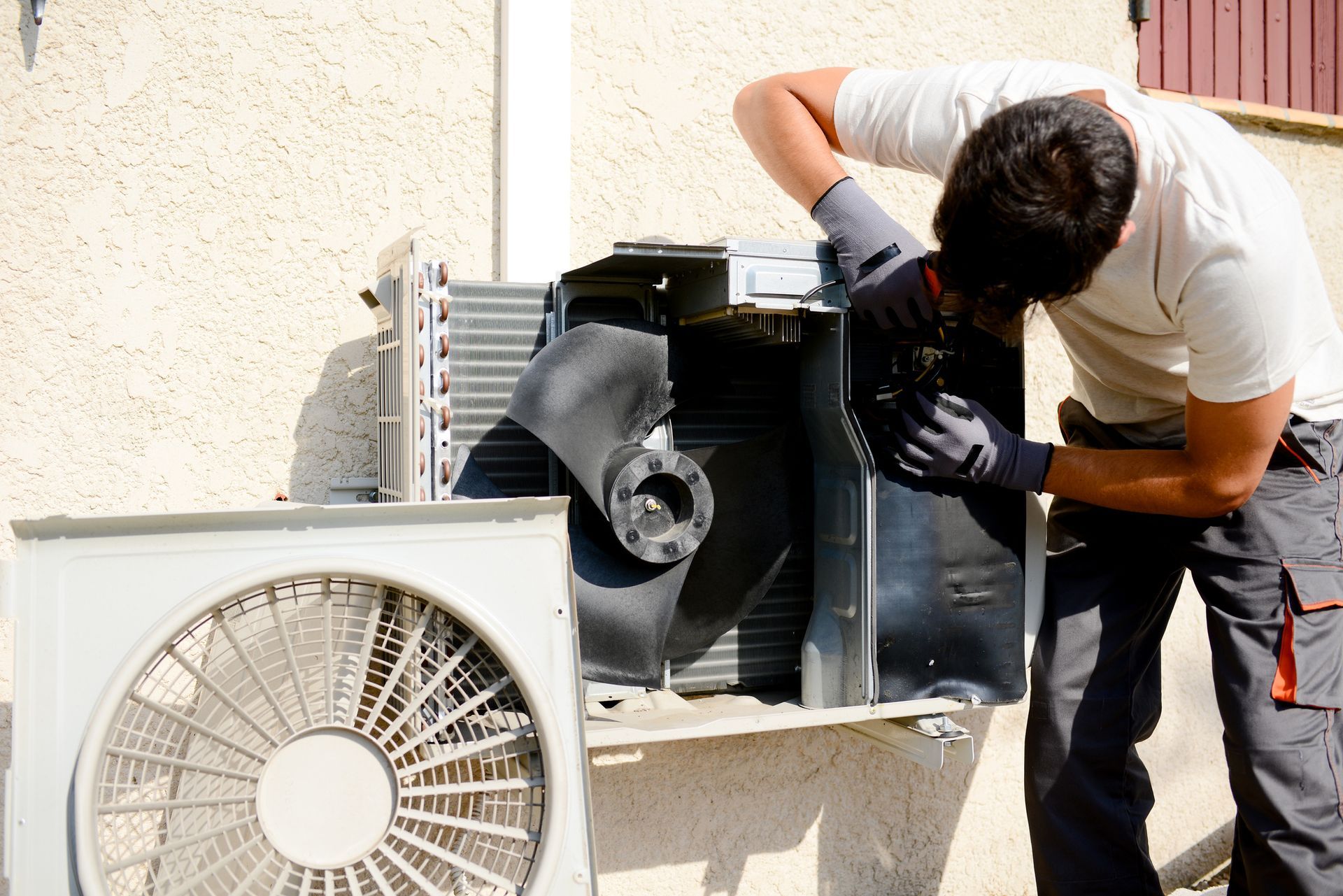 HVAC technician installing outdoor air conditioning condenser unit at home in Gainesville, Florida.