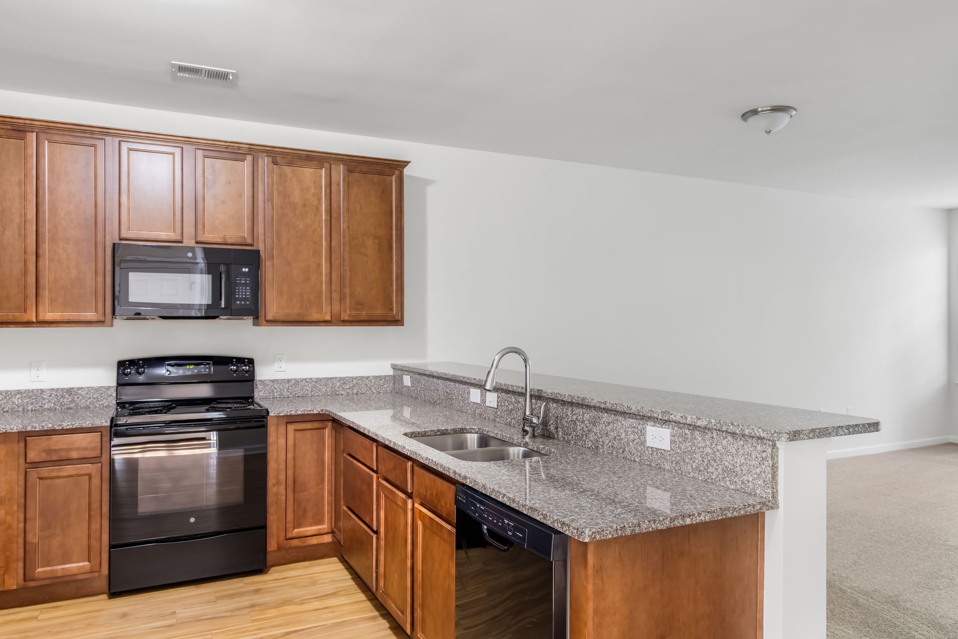 Kitchen with wood cabinets, granite countertops, and black appliances, including an oven and microwave.