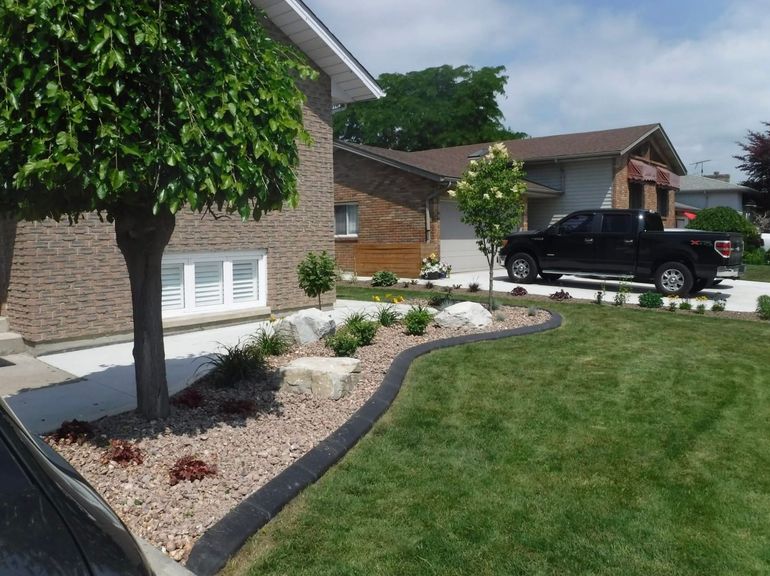 Suburban house with stone and wood siding, landscaped front yard, and black pickup truck in the driveway
