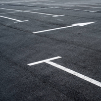 Empty asphalt parking lot with white painted parking space lines