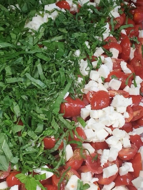 A close up of a salad with tomatoes cheese and basil