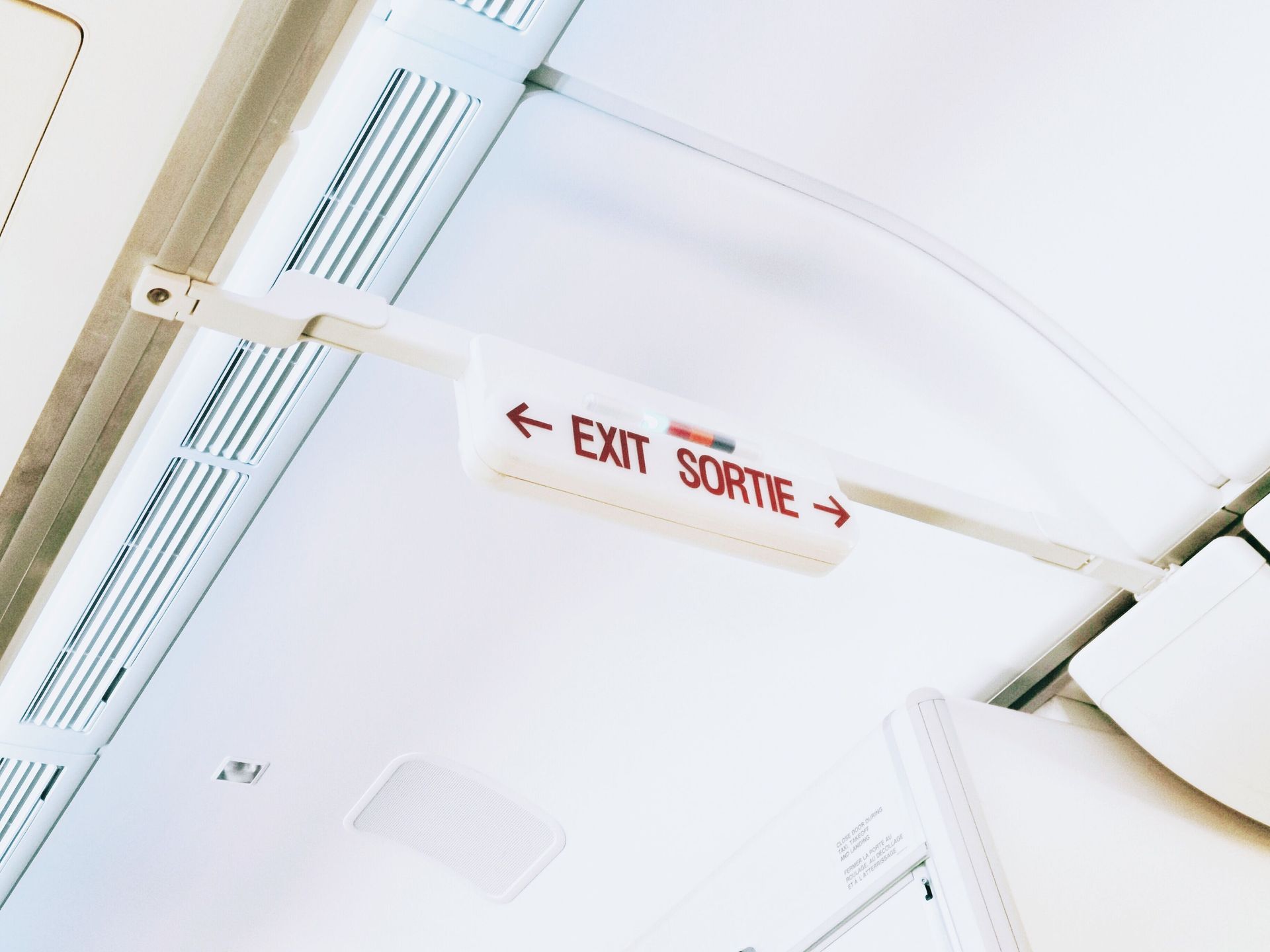 Ceiling-mounted exit sign with arrows pointing left and right on a white bus interior