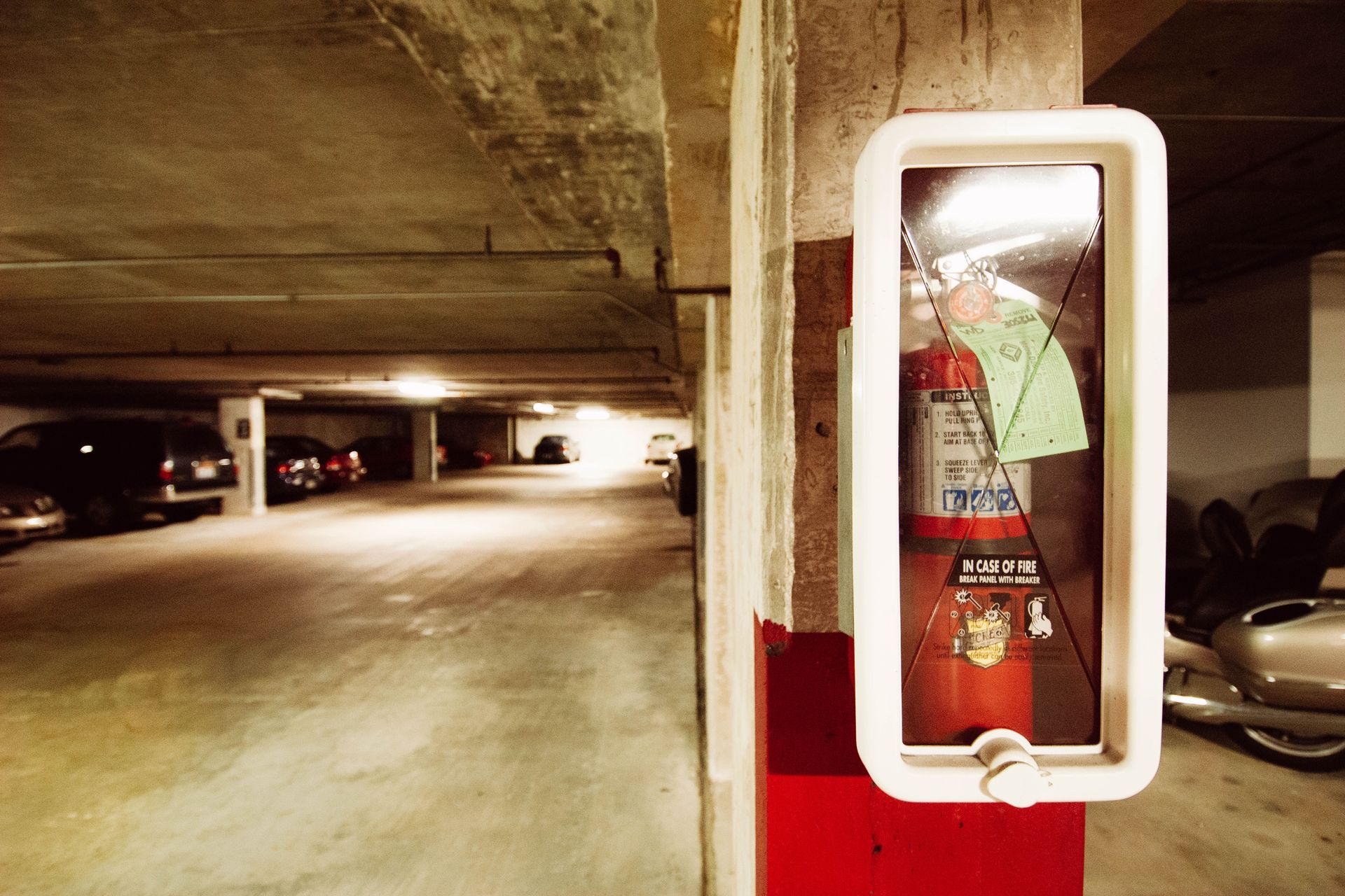 Parking garage with a wall-mounted fire extinguisher in a red and white case