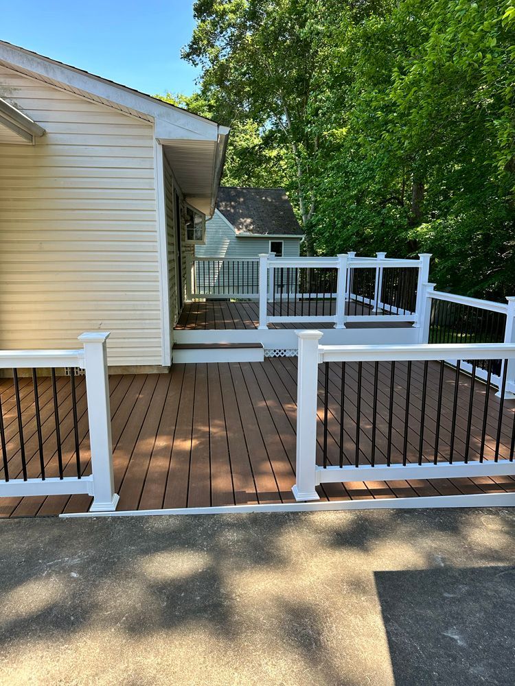 A wooden deck with a white railing and a white house in the background.