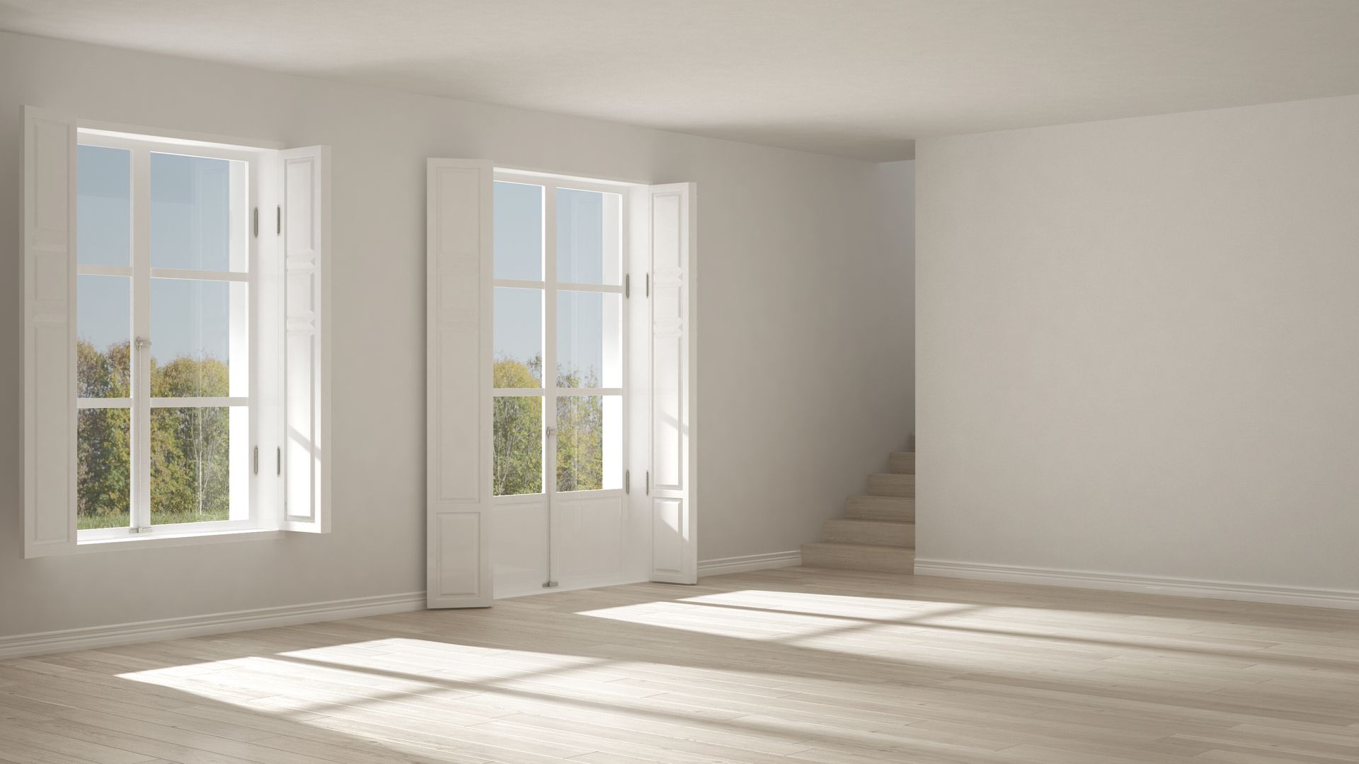 Empty, sunlit room with two large windows and a staircase, bathed in natural light.
