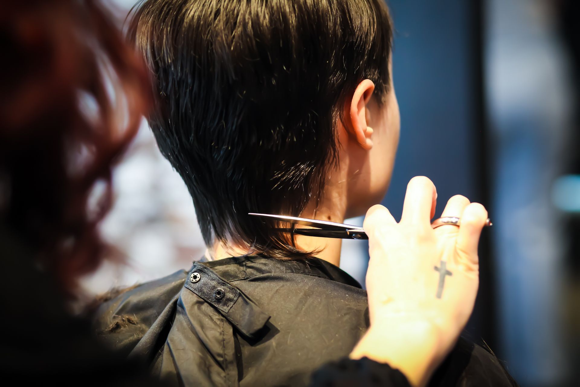 Person getting hair trimmed at the nape of the neck with scissors.