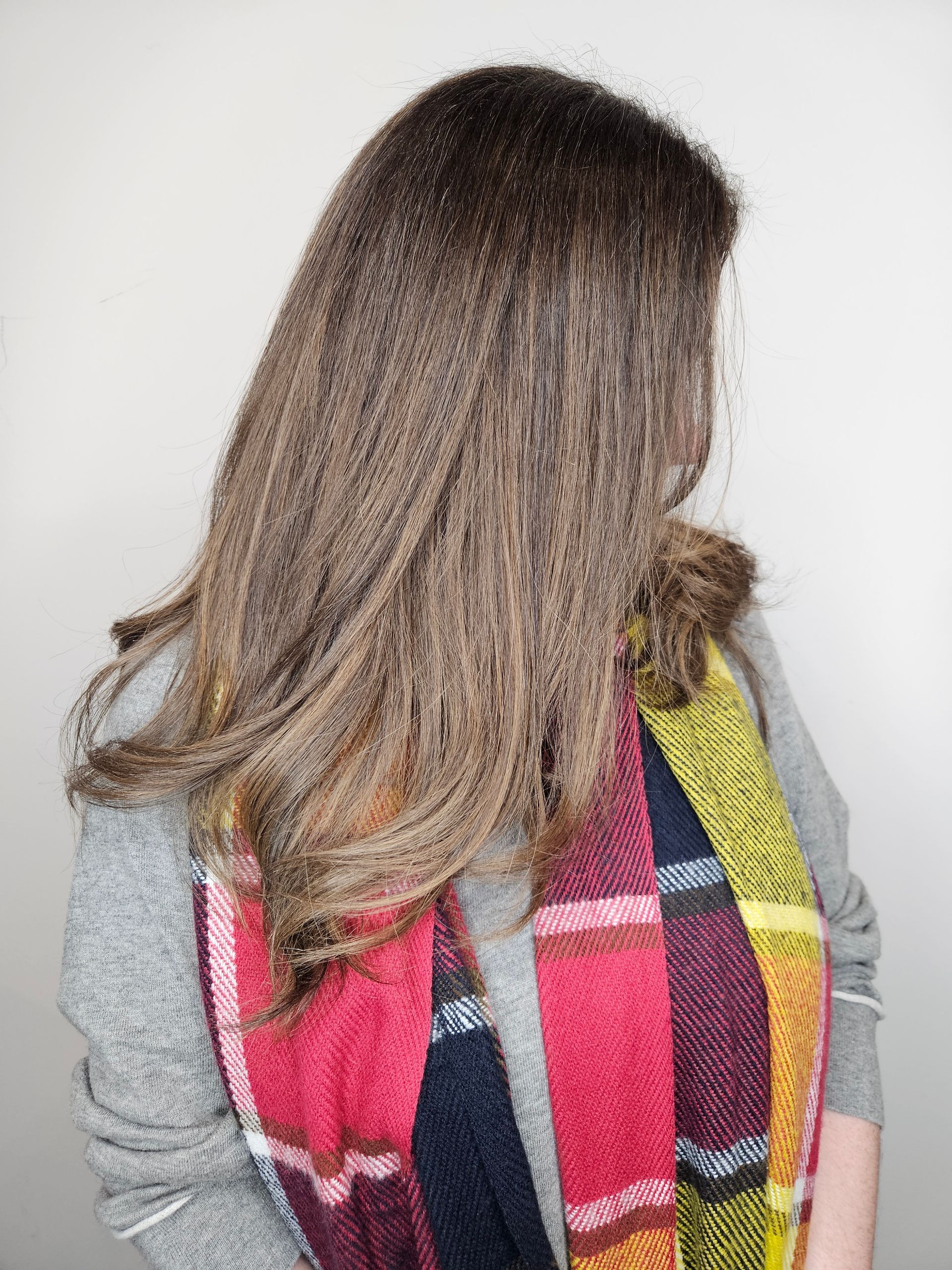 Hairdresser styling hair with spray bottle, arm tattoo visible.