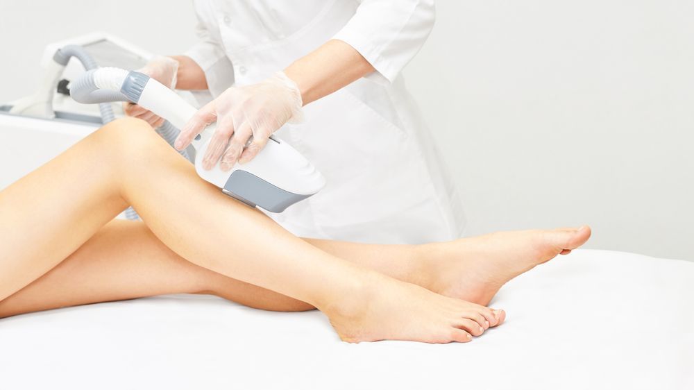 Person Using a Laser Hair Removal Device on a Leg in a Medical Setting — Embrace Cosmetic Clinic in Bundaberg North, QLD