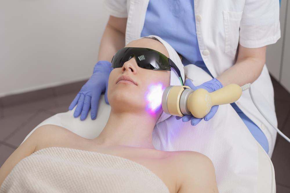 Person Receiving Facial Laser Treatment While Lying on A Clinic Bed — Embrace Cosmetic Clinic in Bundaberg North, QLD
