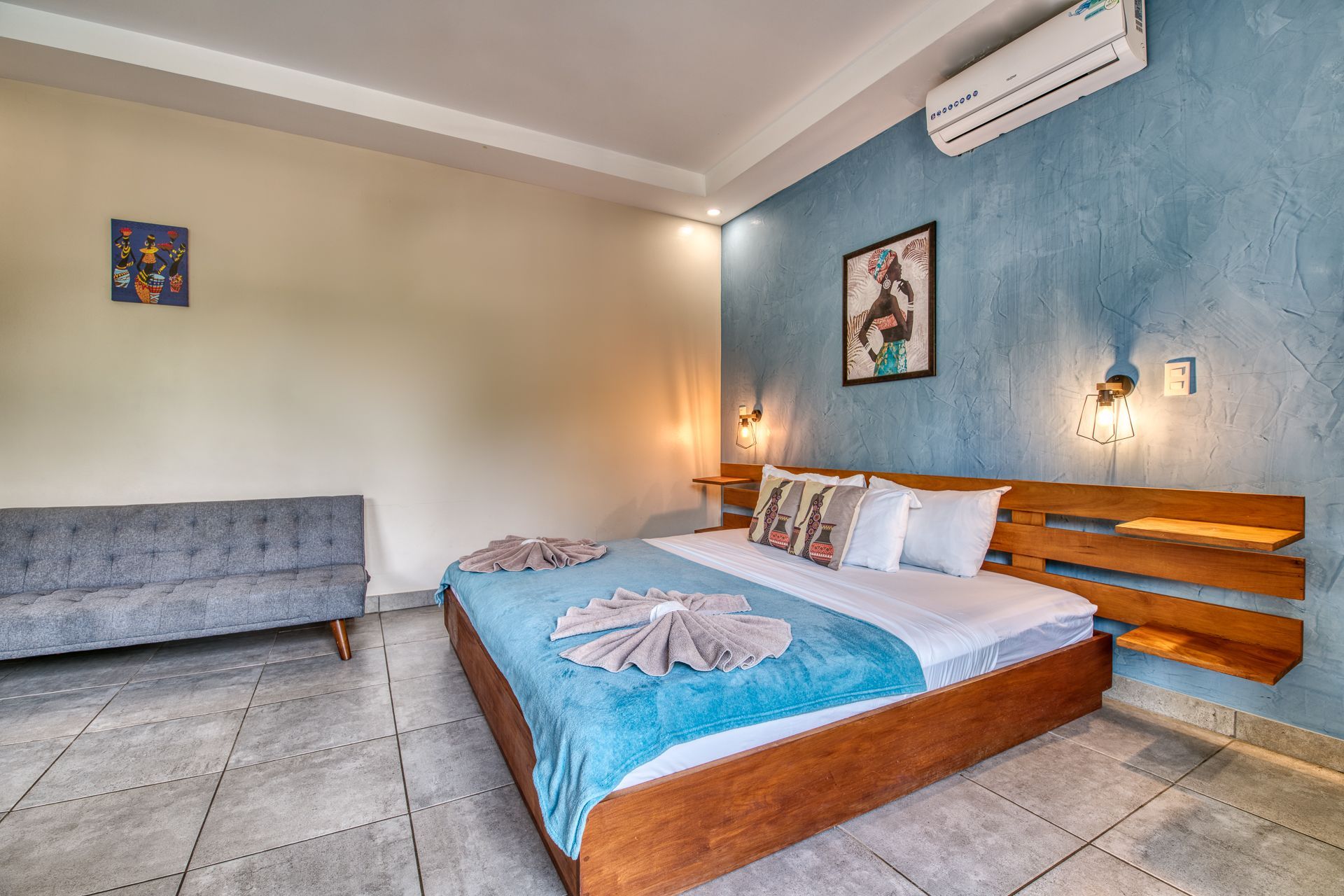 Bedroom with bed, blue wall, sofa, and door to a patio.