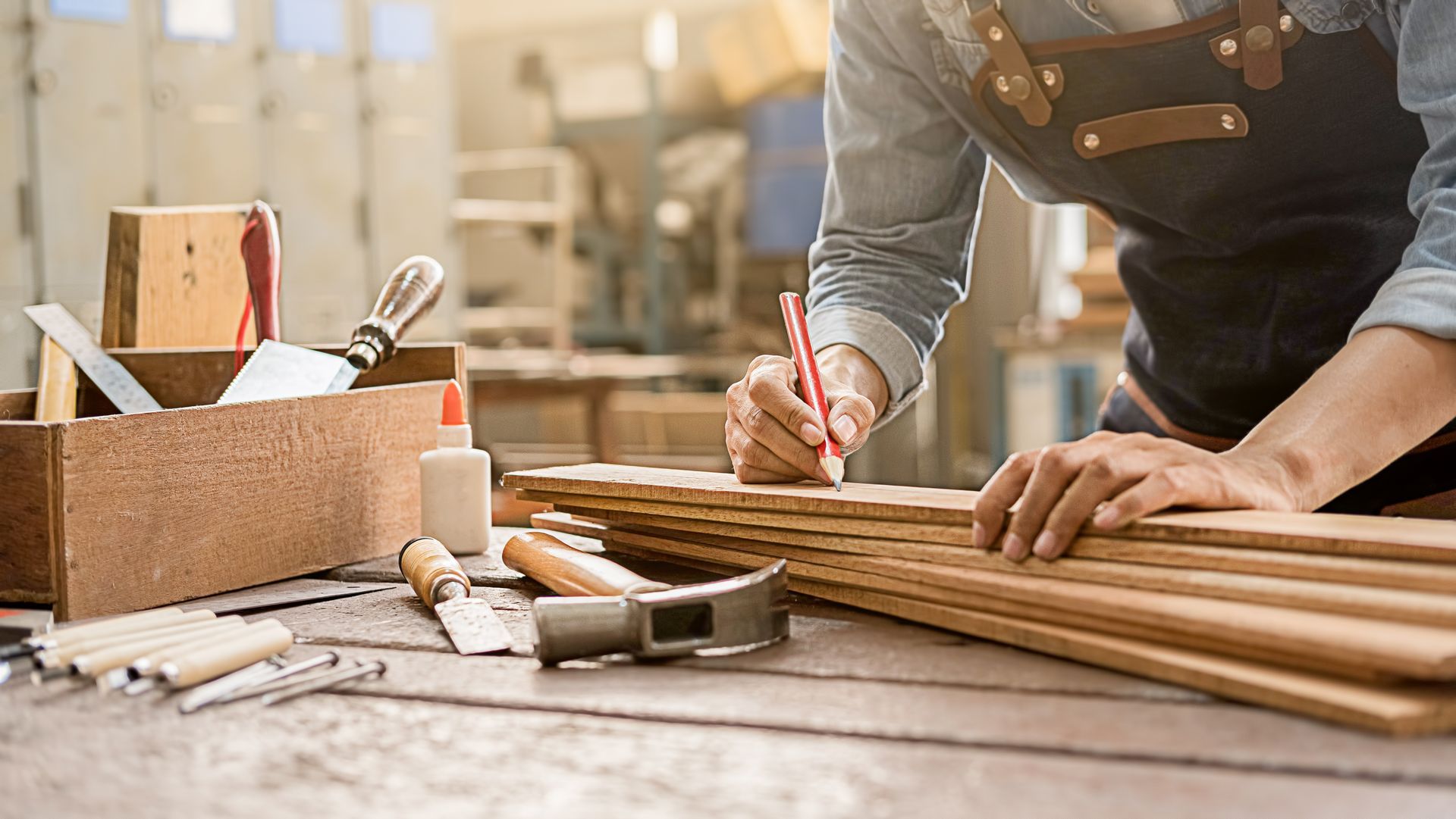 Carpenter measuring and marking wooden planks on a workbench with tools nearby Carpenter measuring and marking wooden planks on a workbench with tools nearby