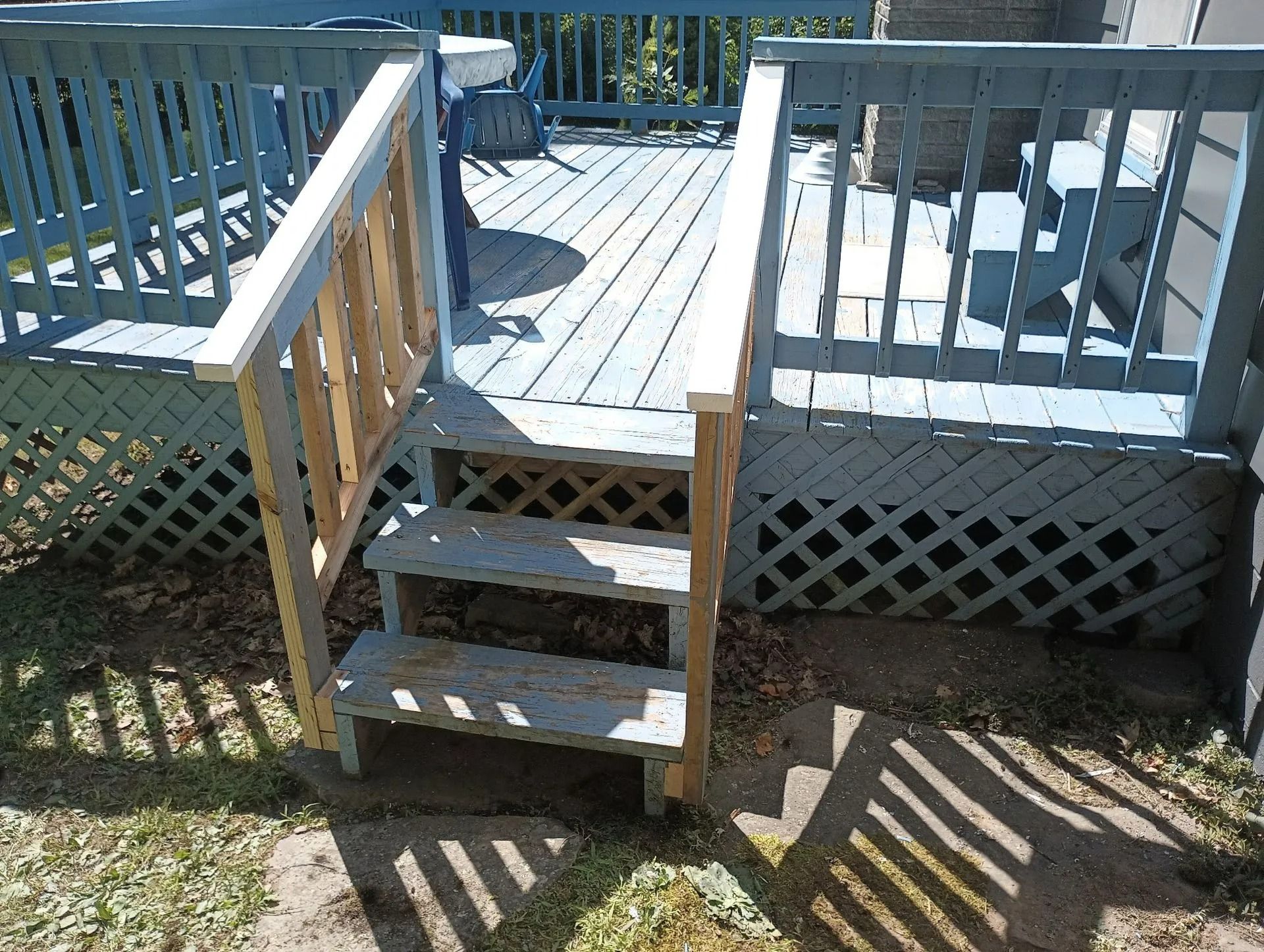 Wooden deck with steps, railings, and lattice panels in bright sunlight