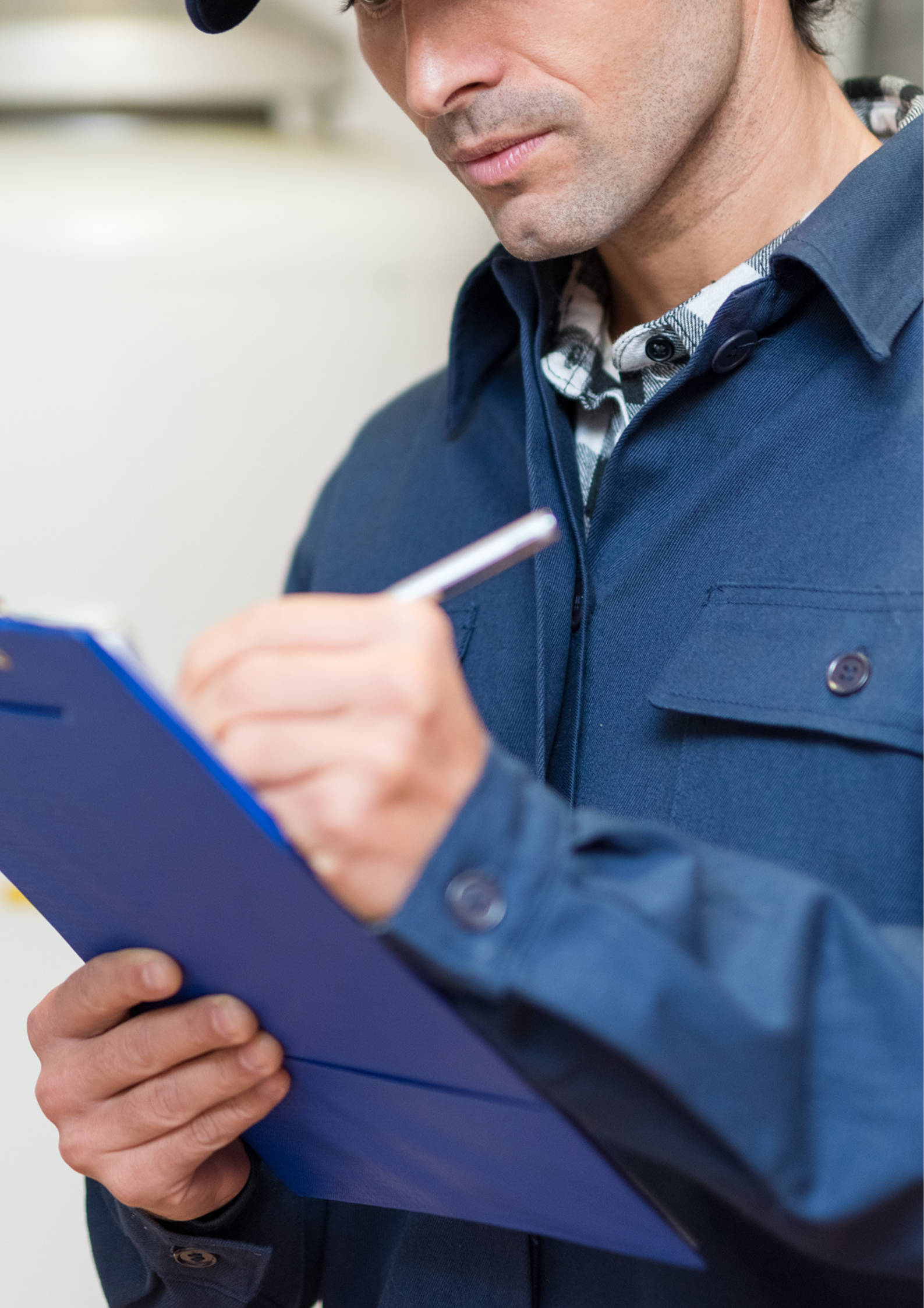 Man writing on a blue clipboard with a pen, wearing a blue shirt.