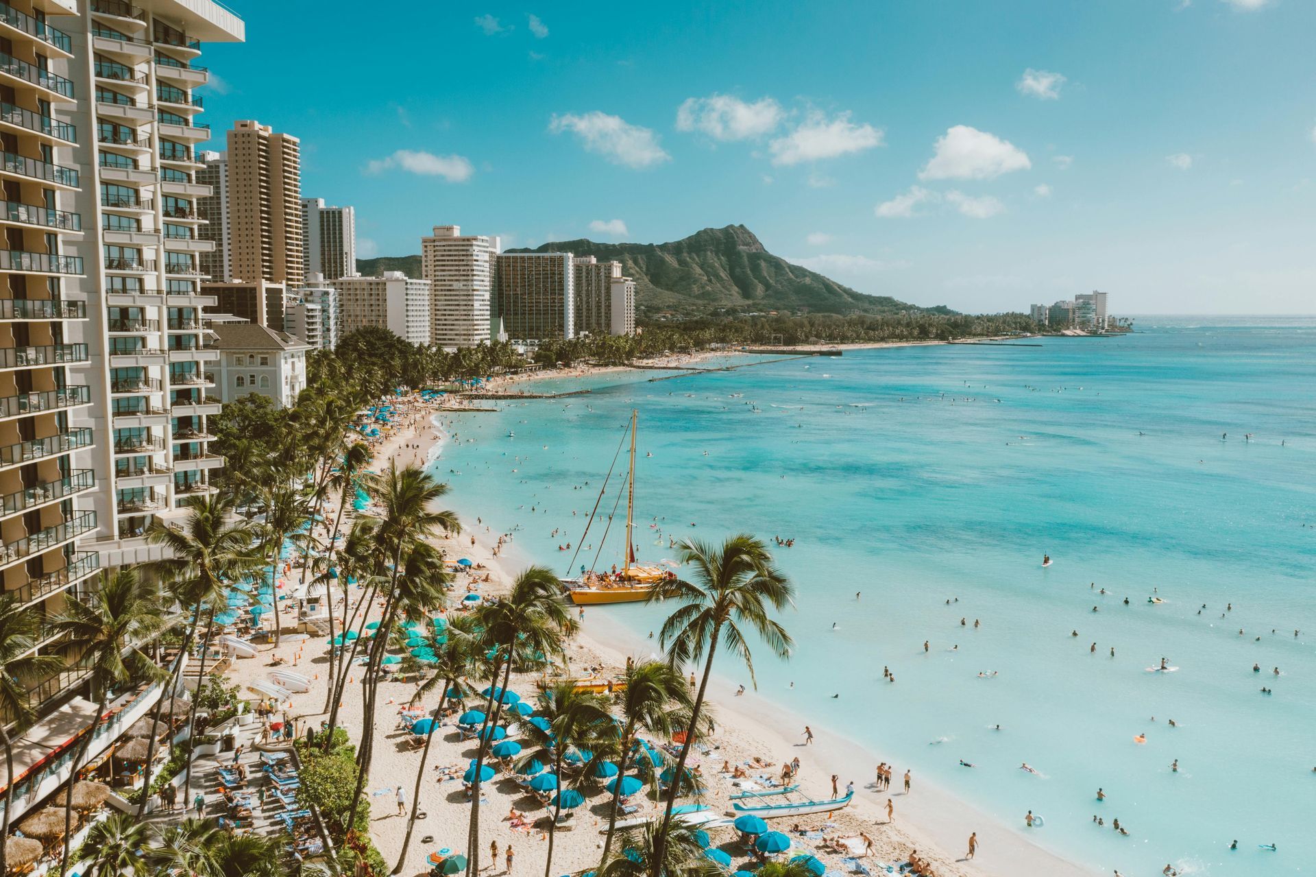 Waikiki Beach, Hawaii. Turquoise ocean, sandy beach, palm trees and hotels. Diamond Head in background.