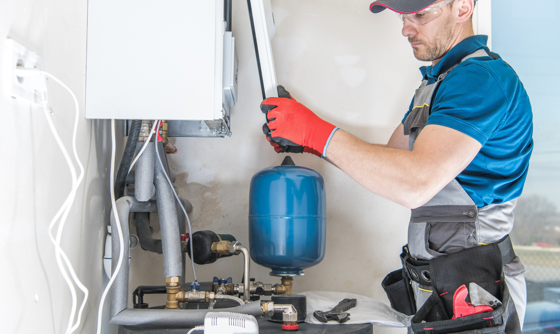 A man is working on a water heater in a room.