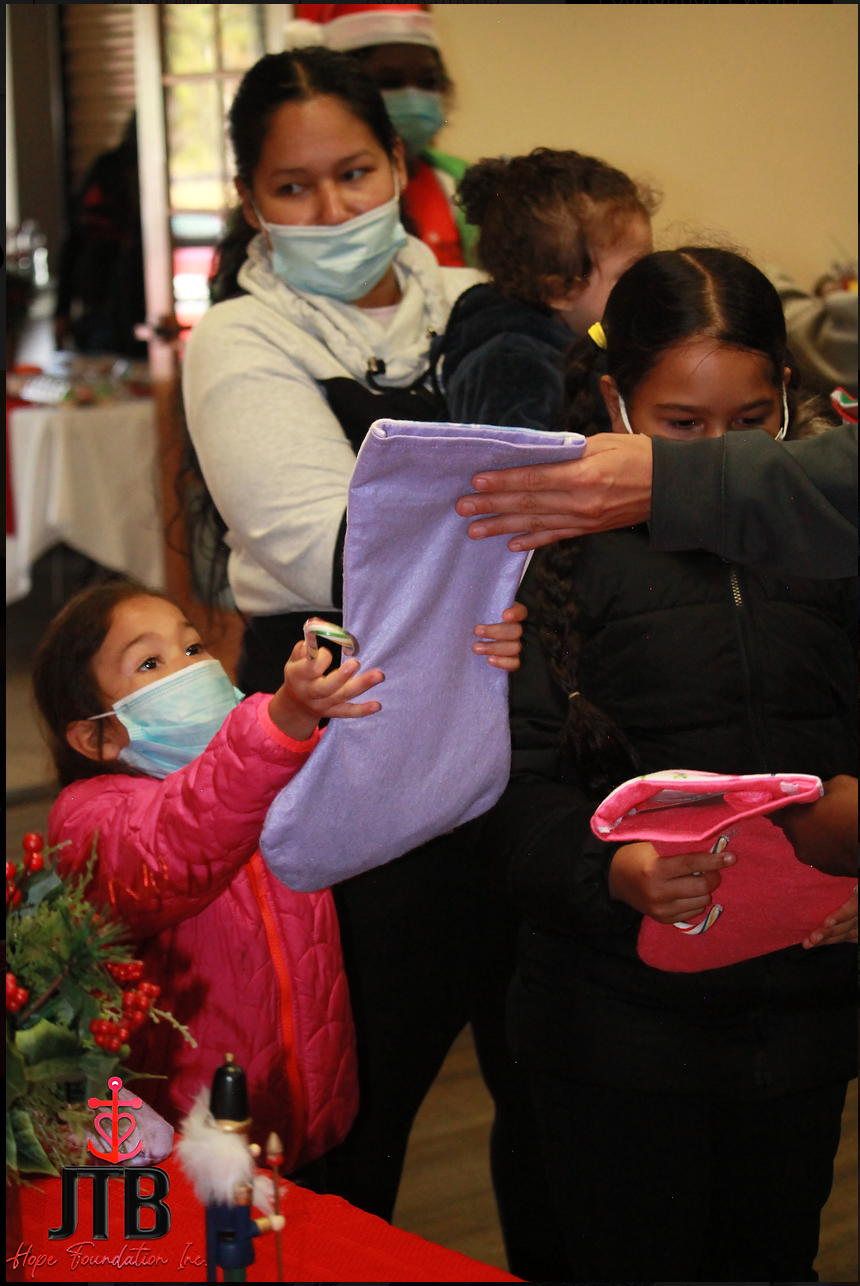 A little girl wearing a mask is holding a purple stocking