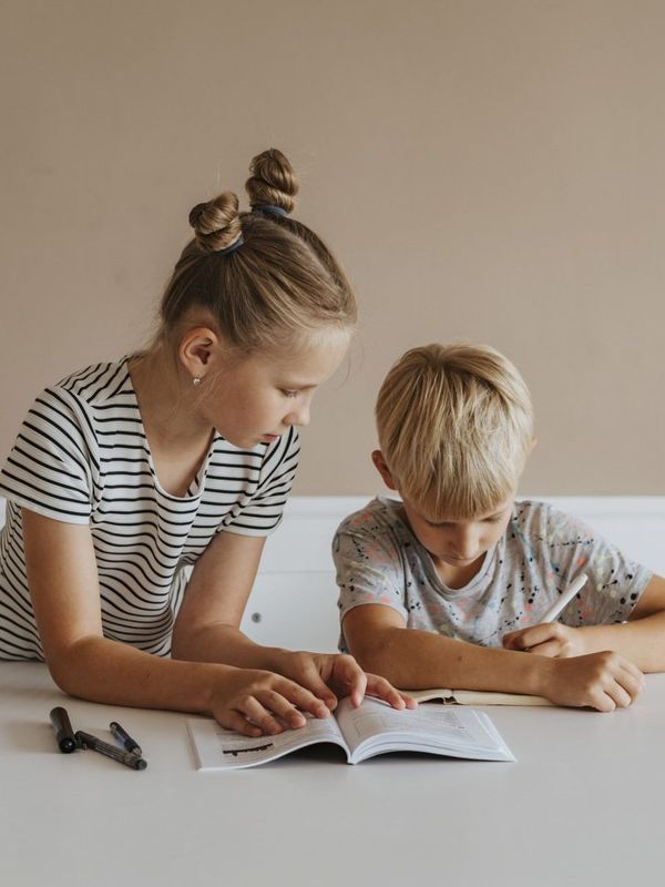 A boy and a girl are sitting at a table doing their homework.
