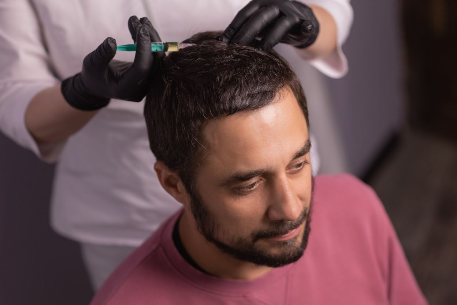 Hairdresser wearing black gloves cutting a man’s short hair in a salon