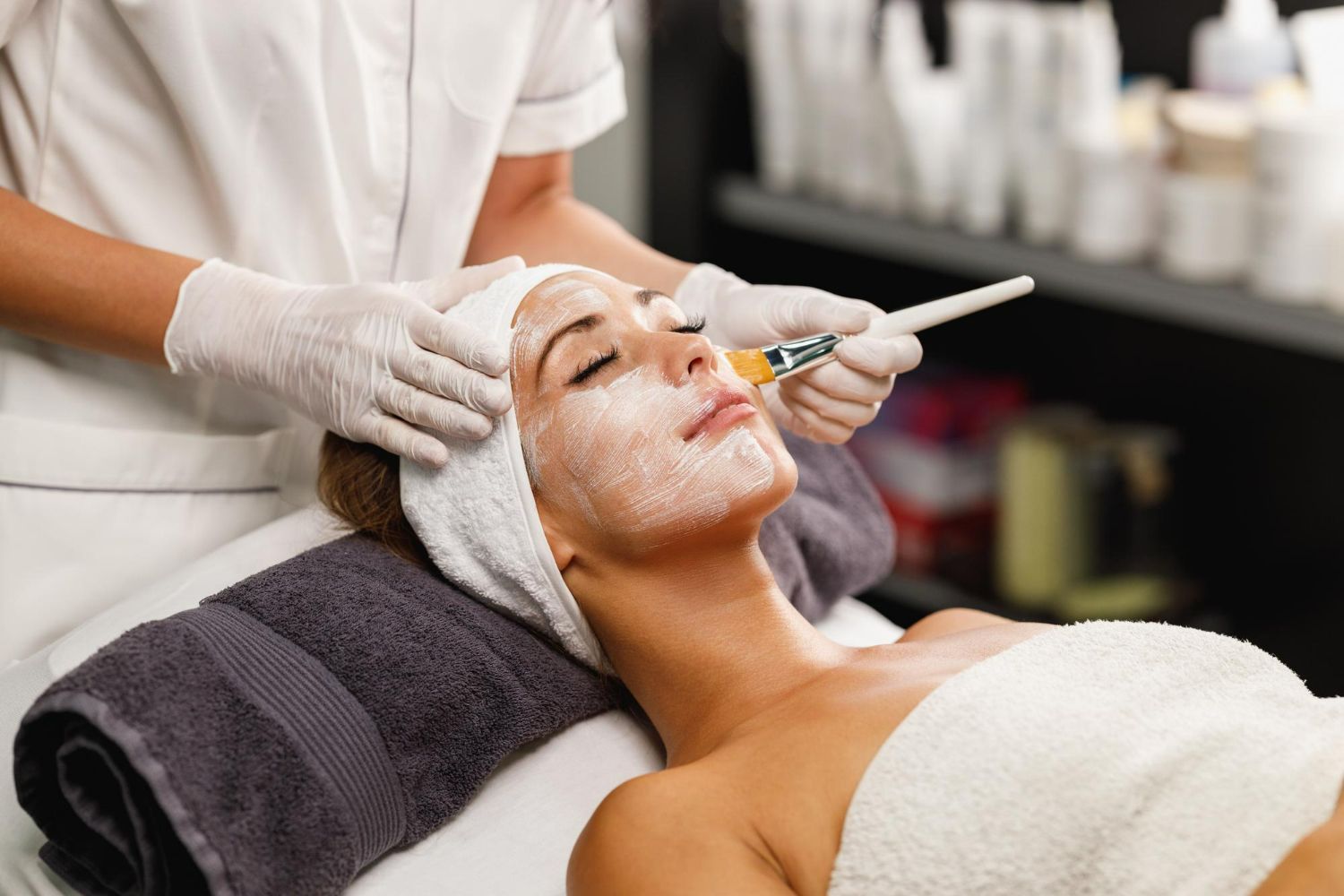 Facial treatment in a spa, with a client receiving cream application by a gloved aesthetician