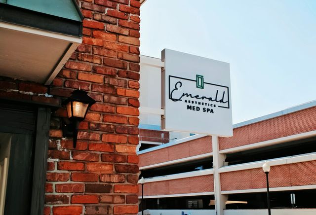 Brick building exterior with a white sign reading “Emerald Spa” and a covered walkway.