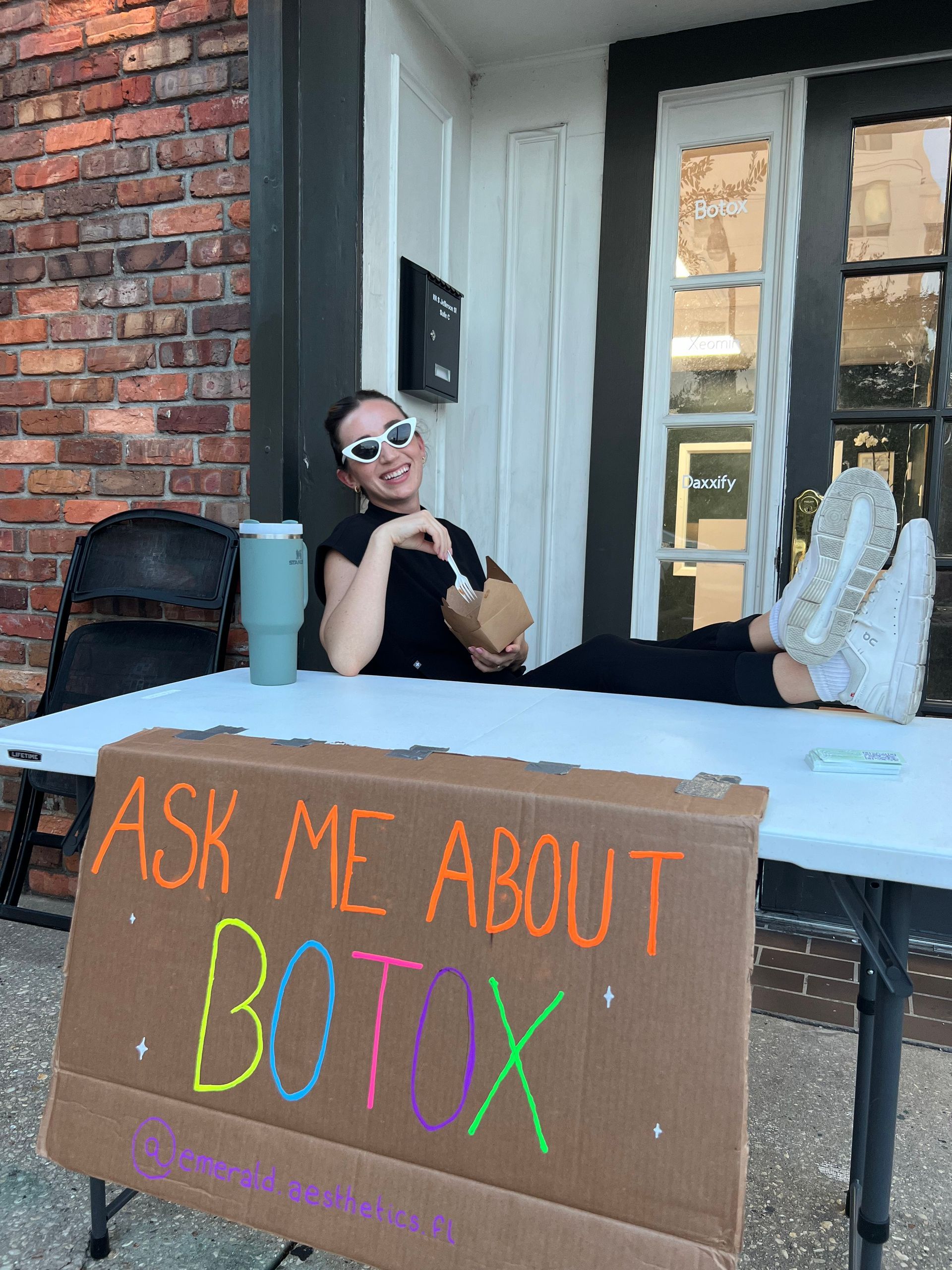 Person reclining at a booth with a sign reading “Ask me about Botox”