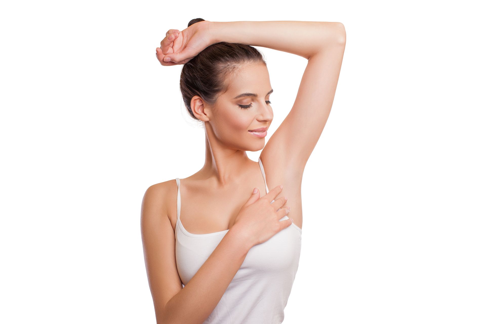 Woman in white tank top raises arm, inspecting her armpit, white background.