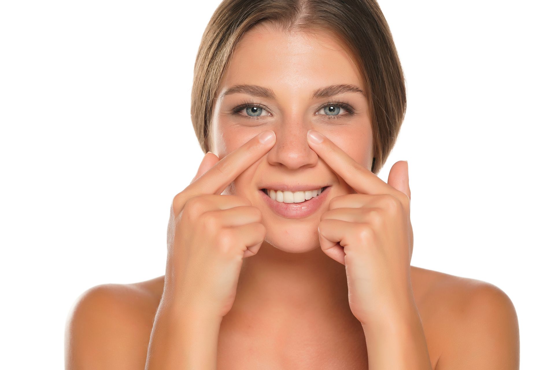 A woman is smiling while touching her nose with her fingers.
