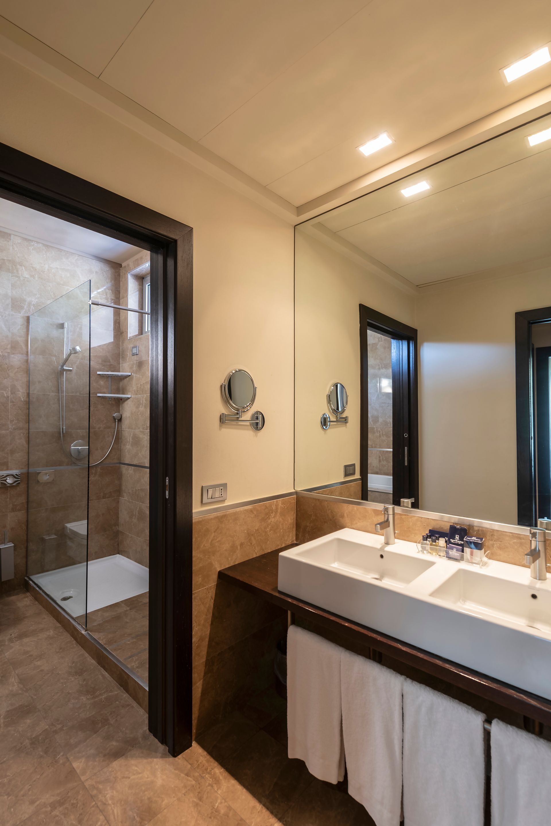 Salle de bain moderne avec douche en verre, lavabo et grand miroir mural